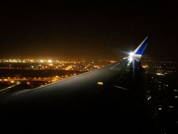 Close-up of airplane wing against sky at night