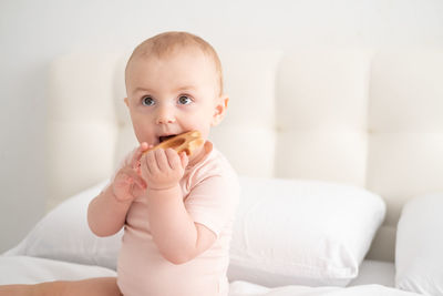 Portrait of cute baby boy sitting on bed at home