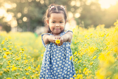 Carefree girl playing with flower on field