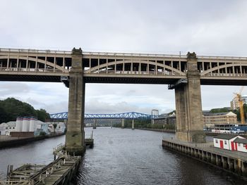 Bridge over river in city against sky