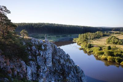 Side view of person standing on rock formation by lake