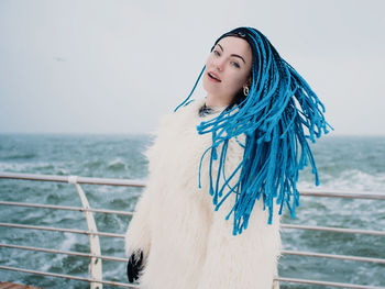 Close-up of young woman standing by railing against sea