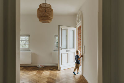 Boy standing by open door at home