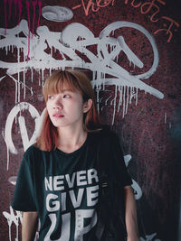 Young woman against graffiti wall