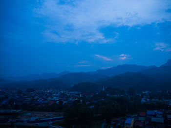 High angle view of townscape and mountains against blue sky