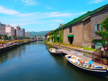 Boats in river in city against sky