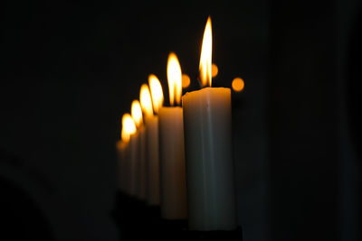 Close-up of illuminated candles in darkroom