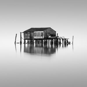 Wooden house by lake against clear sky