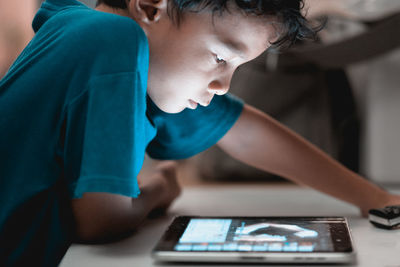 Close-up of boy using digital tablet at table