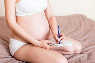 Pregnant woman makes notes in notebook. concept of pregnancy mother waiting for baby.