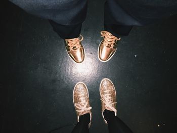 Low section of man and woman with golden shoes on floor