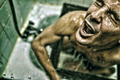 High angle view of shirtless man taking shower in bathroom