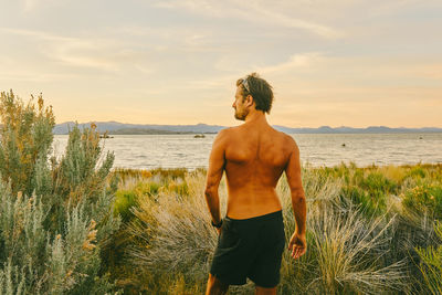 Young man standing in tall grass near mono lake in northern california