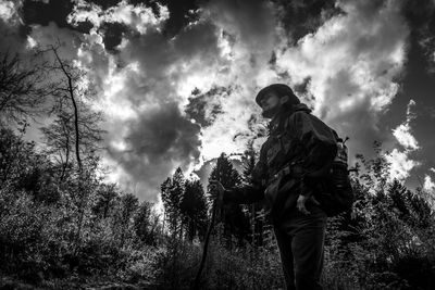 Low angle view of man standing by tree against sky