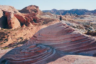 Rear view of man standing on rock formations against sky