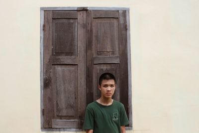 Portrait of boy standing against wall