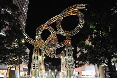 Low angle view of illuminated ferris wheel in city at night