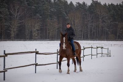 Man riding horse on field during winter