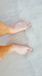 Low section of person standing on sand at beach