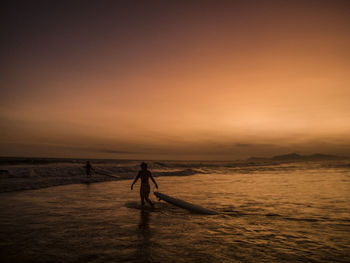 Surfer - sunset at barra da tijuca beach, rio de janeiro