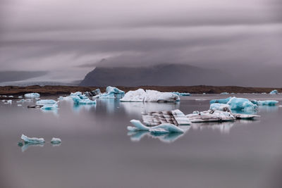 Scenic view of icebergs in sea against sky