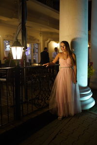 Woman standing by illuminated lighting equipment at night