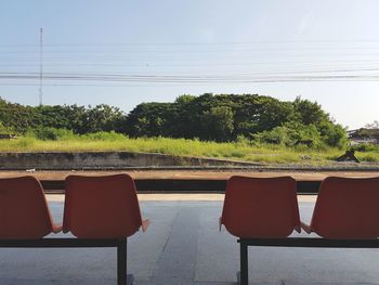 Chairs and trees against sky