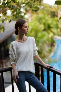 Portrait of young woman looking away while standing outdoors