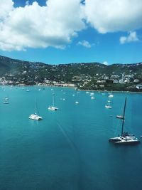 Sailboats moored in sea against sky