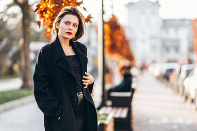 Portrait of young woman standing on street in city