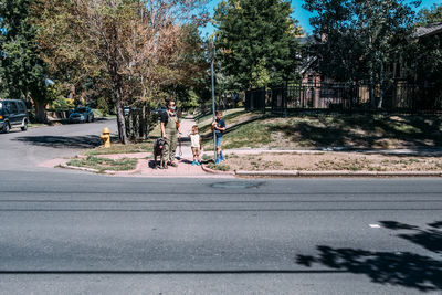 Mother and sons waiting to cross the street with their dog