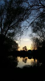 Silhouette trees by lake against sky during sunset