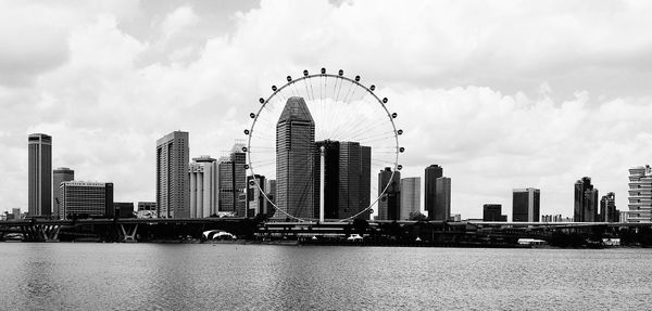 Modern buildings by river against sky in city