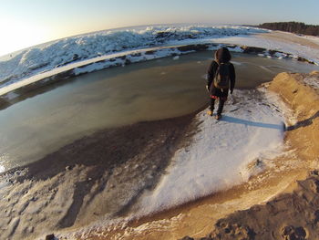 Rear view of man standing on shore against sky