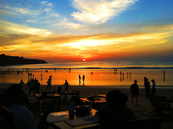 Silhouette people on beach against sky during sunset