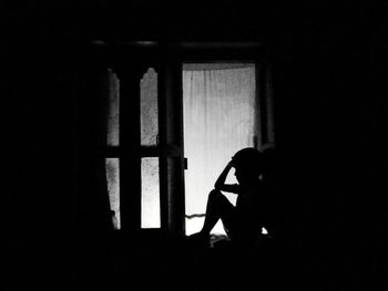 Woman sitting by window in dark room