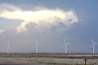 Wind turbines on field against sky