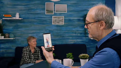 Man using mobile phone while sitting on table