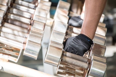 Cropped hand holding dumbbells at gym