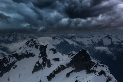 Scenic view of snowcapped mountains against dramatic sky