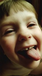 Close-up of shirtless boy sticking out tongue