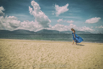 Woman standing on beach against sky