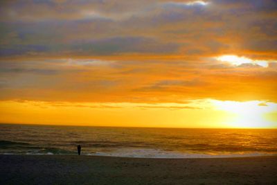Scenic view of sea against dramatic sky during sunset