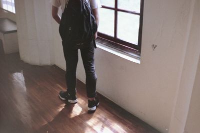 Low section of student standing on hardwood floor at home