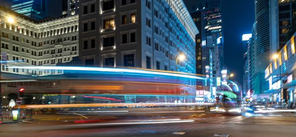 Light trails on city street by buildings at night