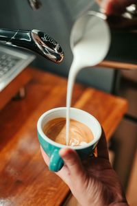 Cropped hands of person preparing coffee at cafe