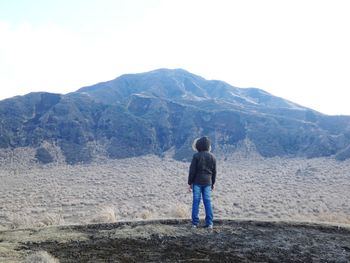 Rear view of man standing on mountain against sky