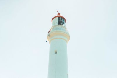 Low angle view of lighthouse by building against clear sky