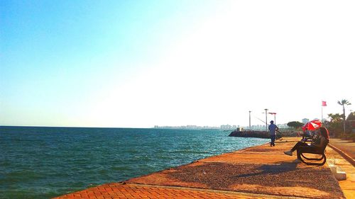 Woman looking at sea against clear sky