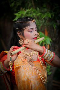 Side view of young woman as raha playing flute outdoor